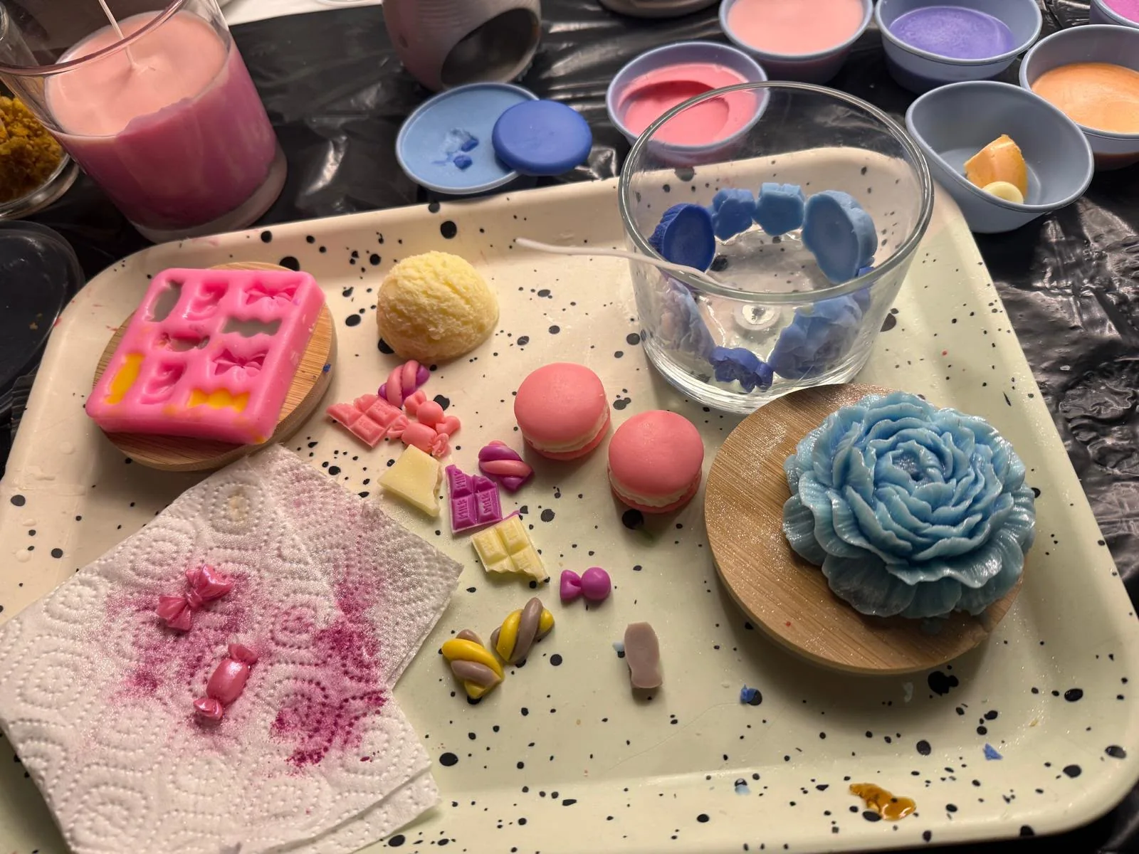 Werkbank in der LUNOWIA Manufaktur mit handgegossenen Wachs-Details, Macarons und einer Wachsblüte